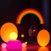 3D render of abstract rainbow shapes and glowing orbs with blurred silhouettes of people in a dark background, symbolizing connection, privacy, and...